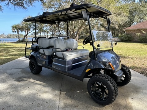 Six seater golf cart on lift near water.